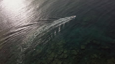 motorboat leaves white wake trail over shallow transparent sea waters, puglia in italy