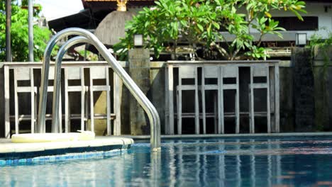 Static-shot-of-an-entry-at-a-beautiful-pool-inside-a-hotel-complex-on-bali-in-indonesia-with-reflecting-water-and-plants-in-the-background