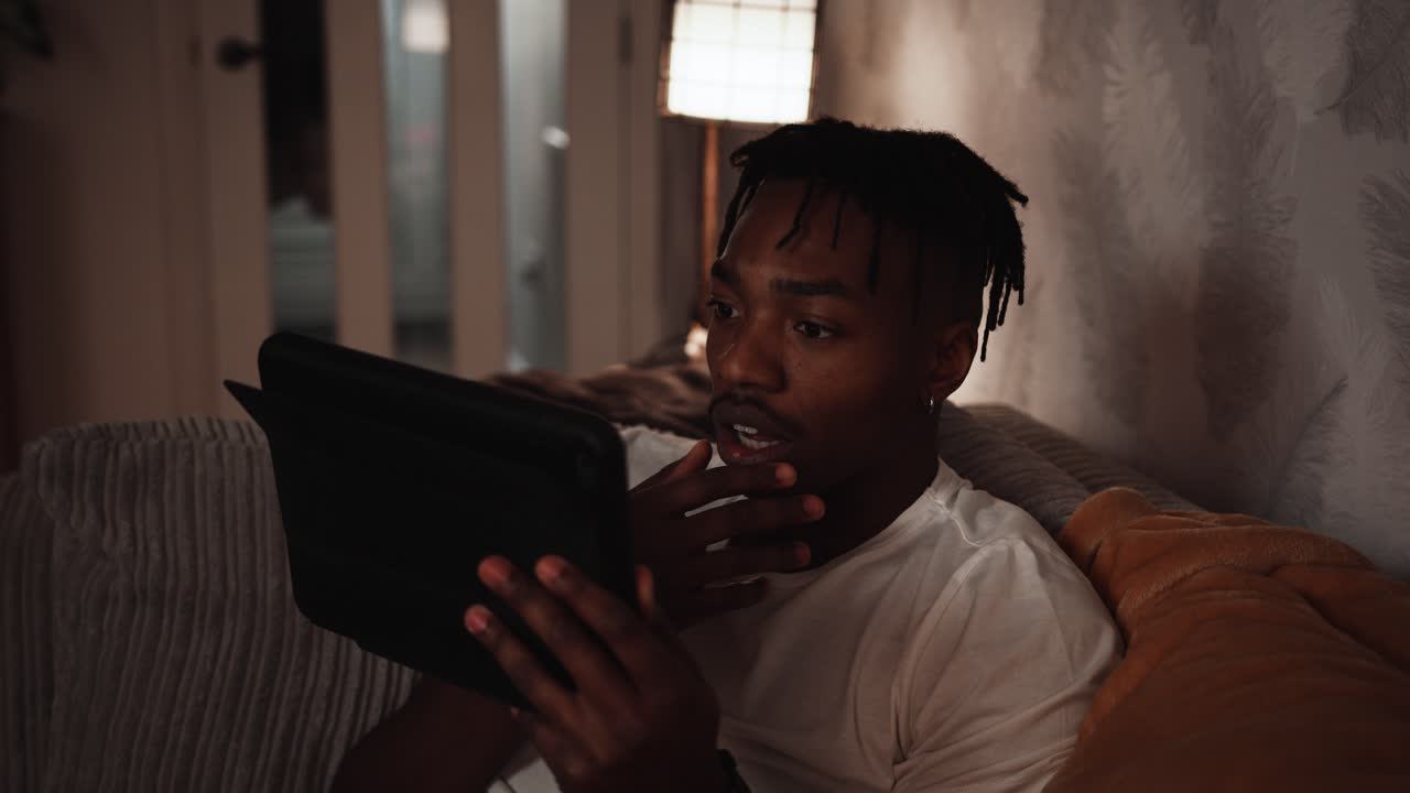 Young black male acts shocked while looking at his tablet device