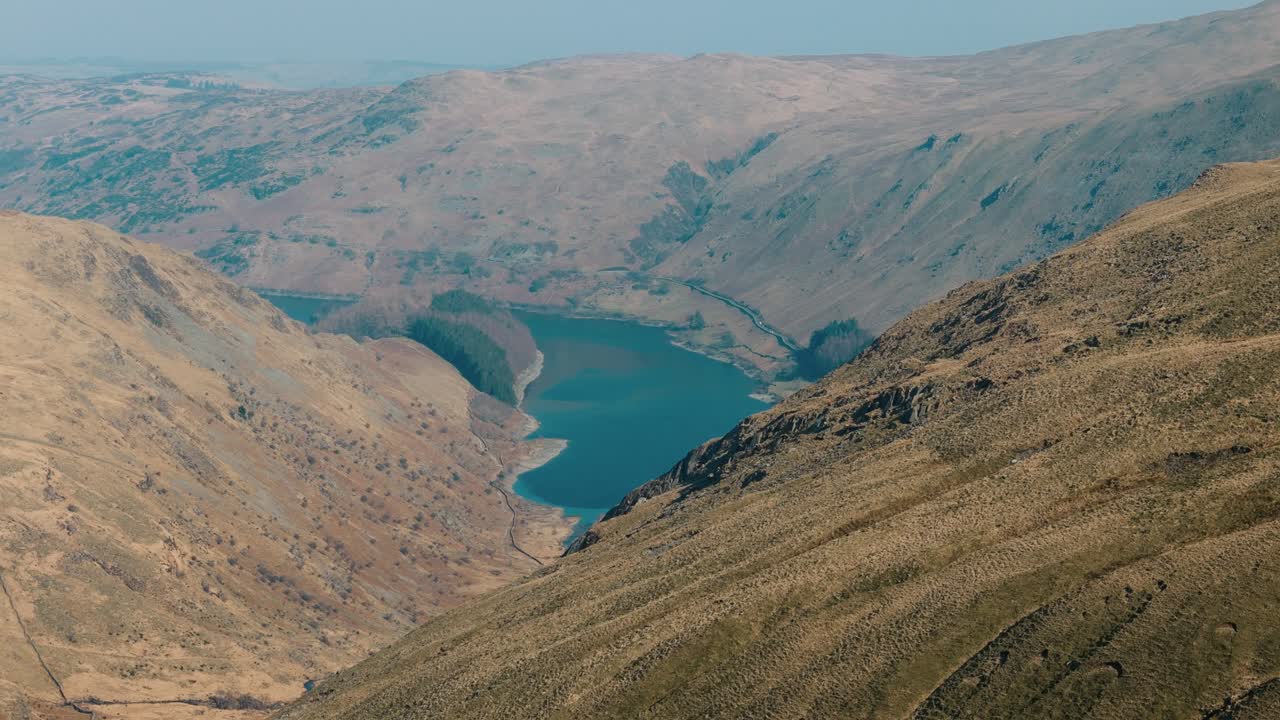 High orbit left reveal over lake and surrounding hills in rural northwest England, intro establishing aerial