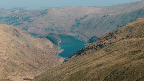 high orbit left reveal over lake and surrounding hills in rural northwest england, intro establishing aerial