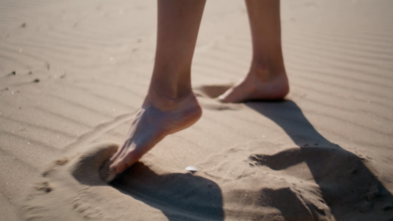 Legs making footprints sand beach sunny day closeup. Unknown woman stepping