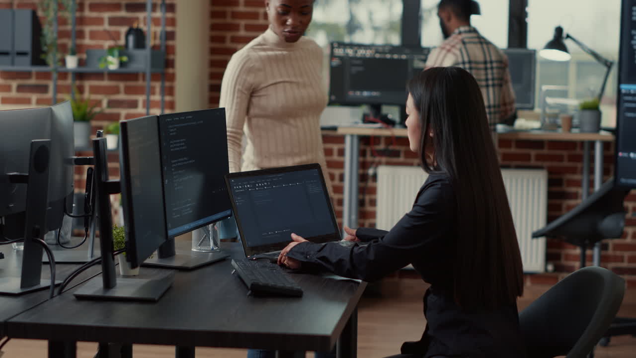 Coder holding laptop with coding interface entering software development agency office sitting down
