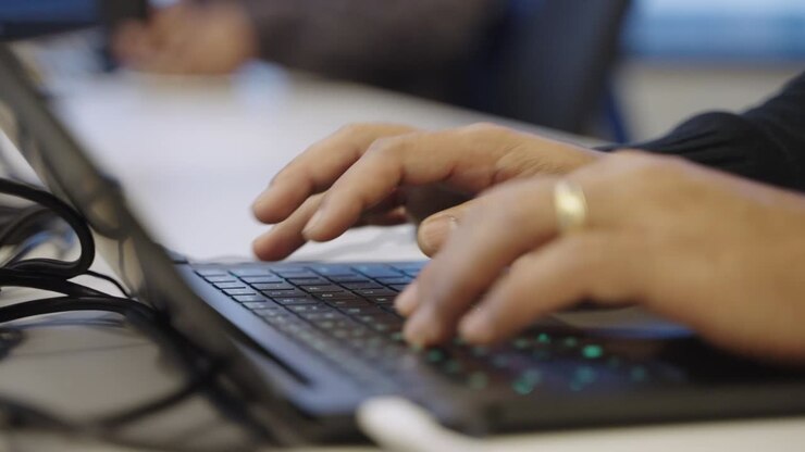 Close up of anonymous married person's hands typing on laptop keyboard in office