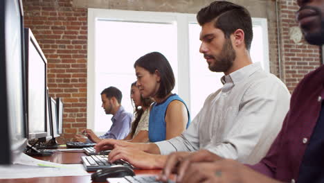 Staff-Use-Computers-Sitting-At-Desks-In-Office-Shot-On-R3D