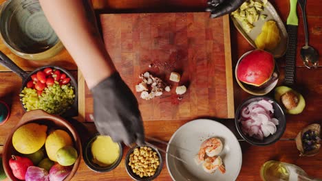 vista directa hacia abajo de un chef profesional cortando y rebanando tentáculos de pulpo, vieiras y langostinos en trozos pequeños en una tabla de cortar, preparándose para un auténtico entrante de ensalada de marisco ceviche