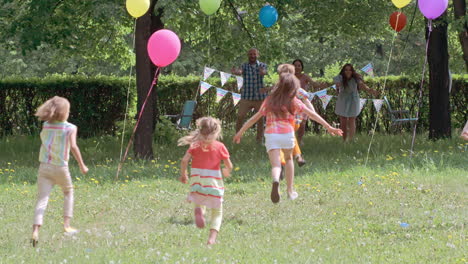 rear view of children running to hug their parents at a birthday party in the park