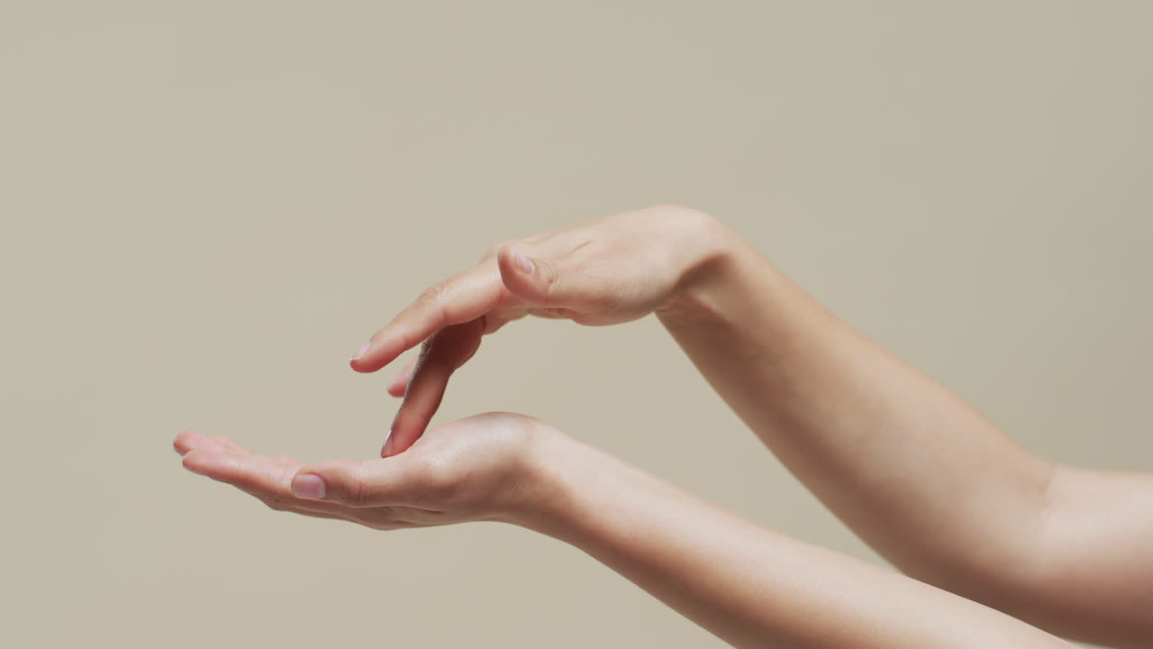 복사 공간과 베이지색 배경에 있는 아시아 여성의 손, 슬로우 모션