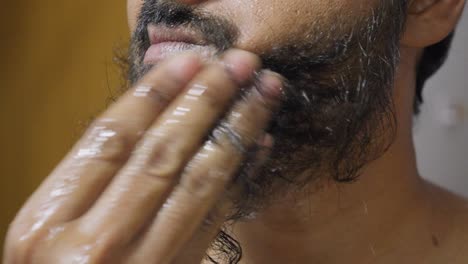 a close-up footage of a south asian man wetting his beard with water, with blurred background. hygiene concept