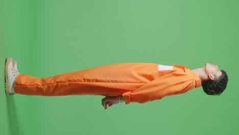 vista lateral del cuerpo completo de un prisionero masculino asiático con esposas de pie en el fondo de la pantalla verde, mirando arriba y abajo sacudiendo la cabeza molesto por lo que hizo