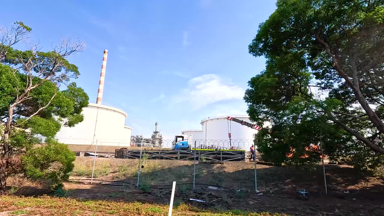 Industrial site in Geelong with trees and clear blue sky. Daytime lighting highlights factory structures and surrounding greenery
