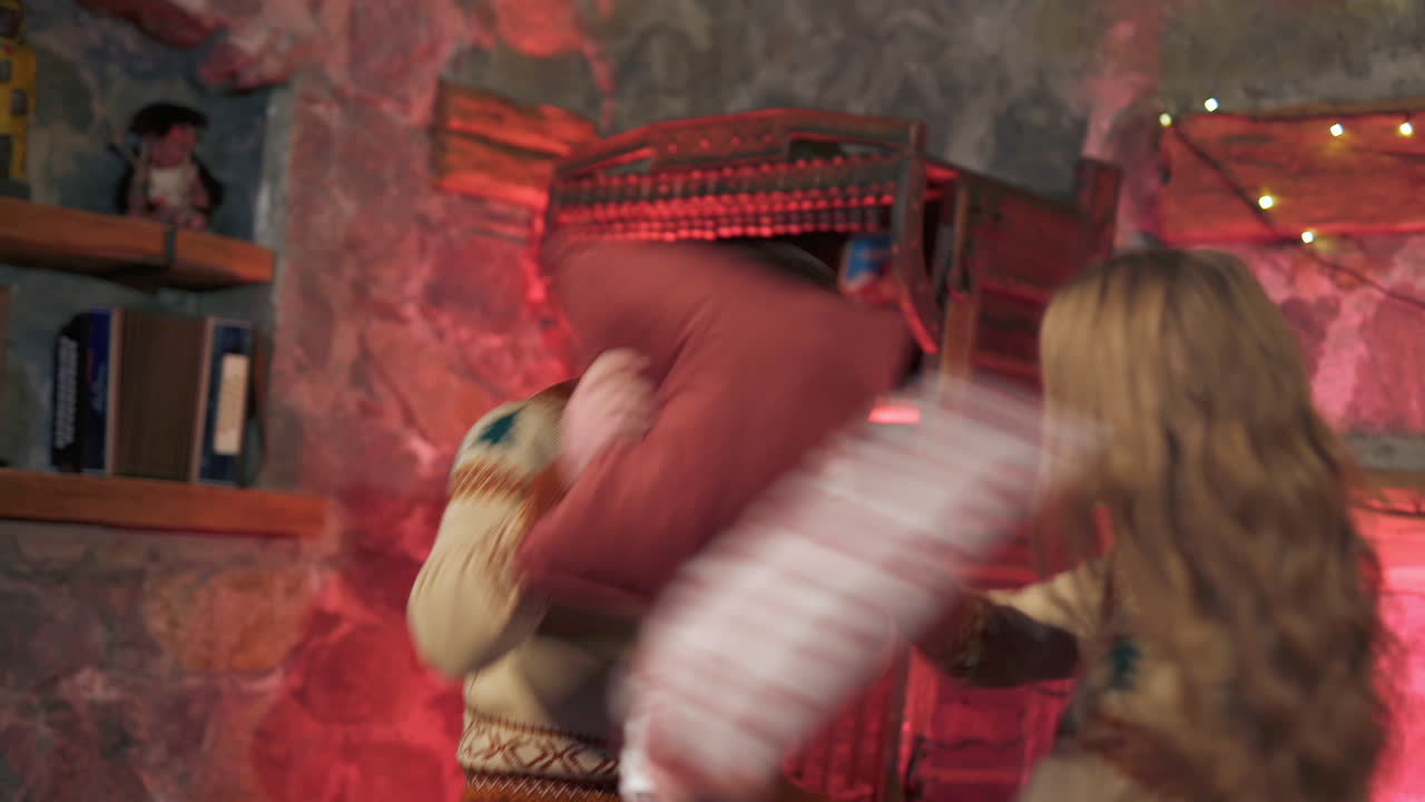 Couple in love on bed with pillows. Happy young woman and man having pillow fight in romantic bedroom at Christmas time.