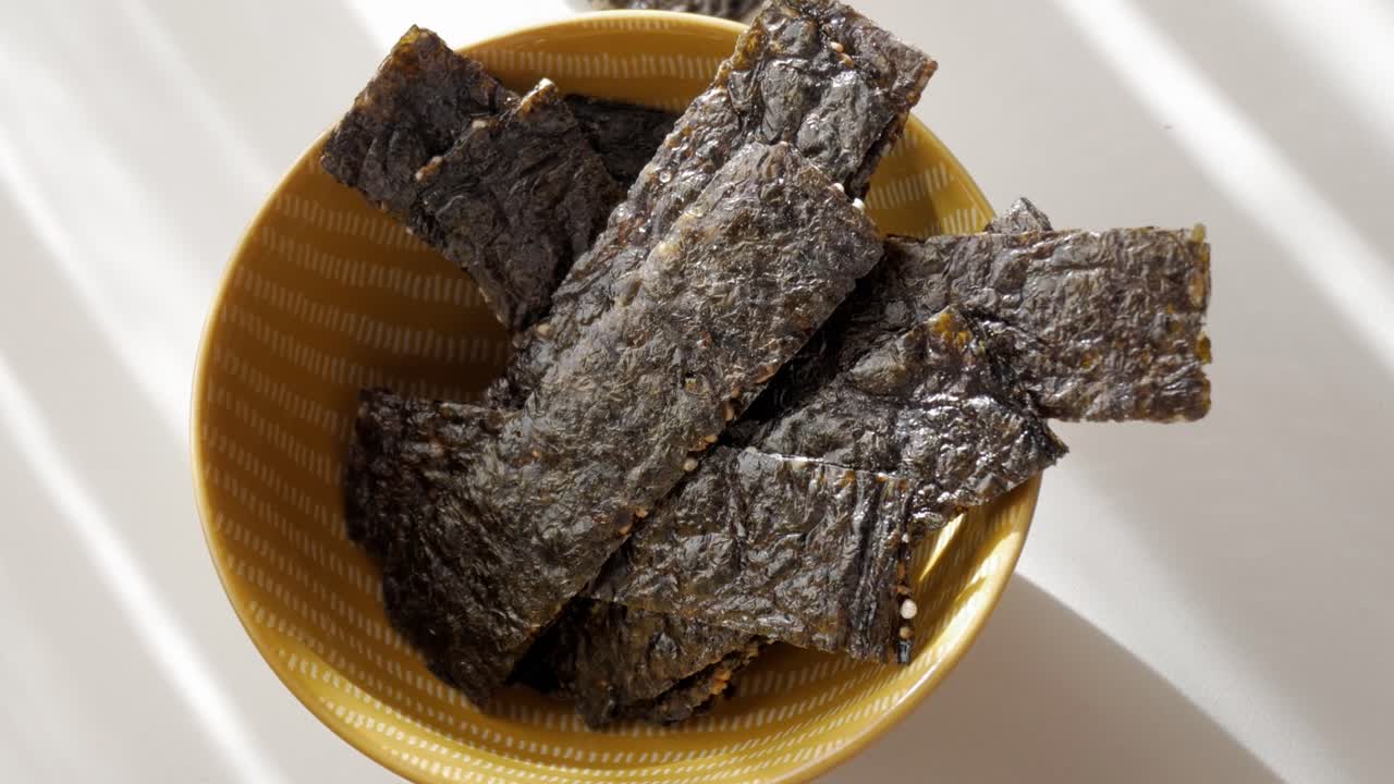 Crispy seaweed snack in a bowl with light reflections
