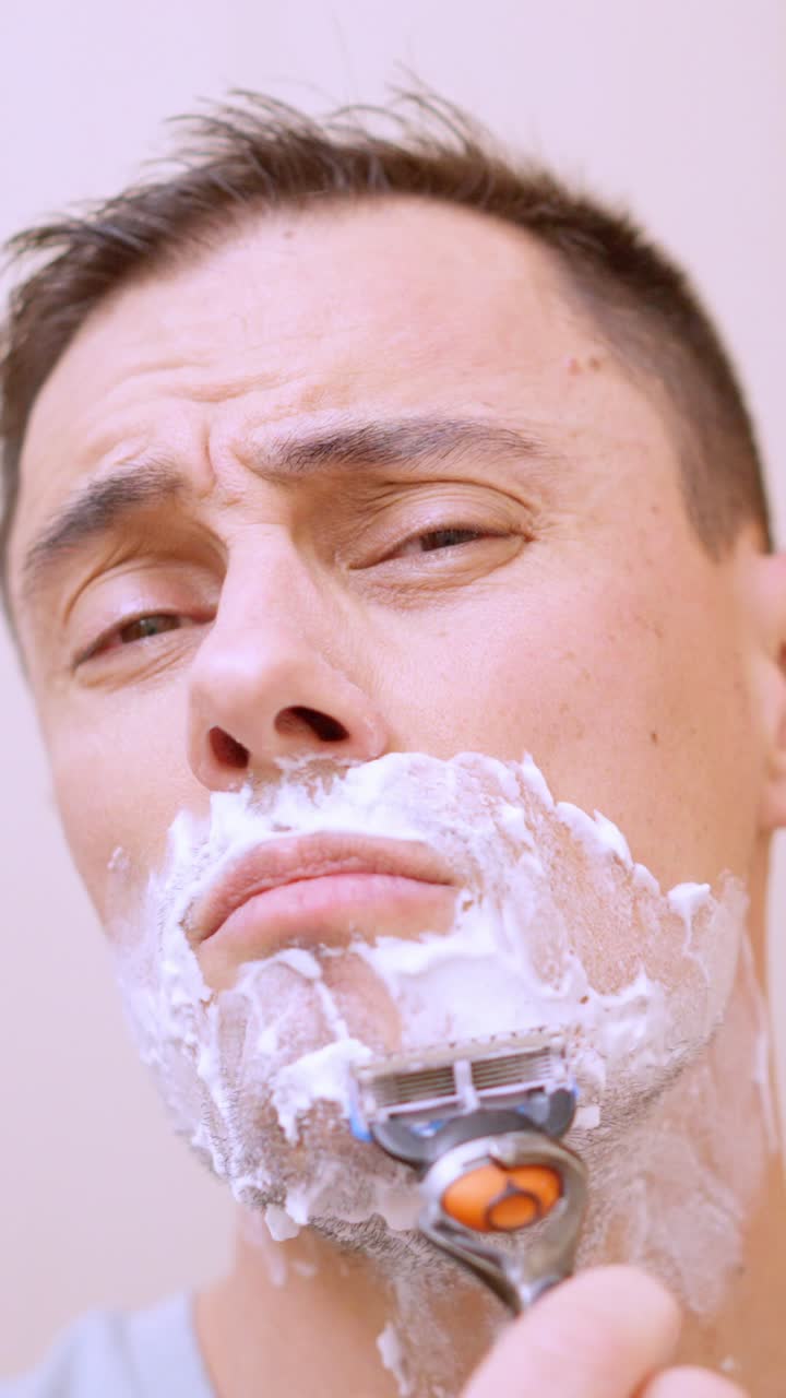 남자 가 욕실 에서 수염 을 면도 하고 있다