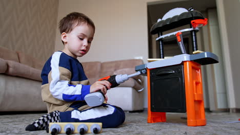 child plays happily with toys. a young boy engages with a colorful toy workbench, hammering toy pieces on the floor in a cozy indoor setting
