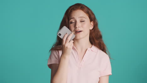 redheaded girl in front of camera on turquoise background.