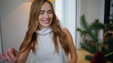 glückliche frau untersucht xmas-spielzeug zu hause porträt. neujahrsfeier konzept