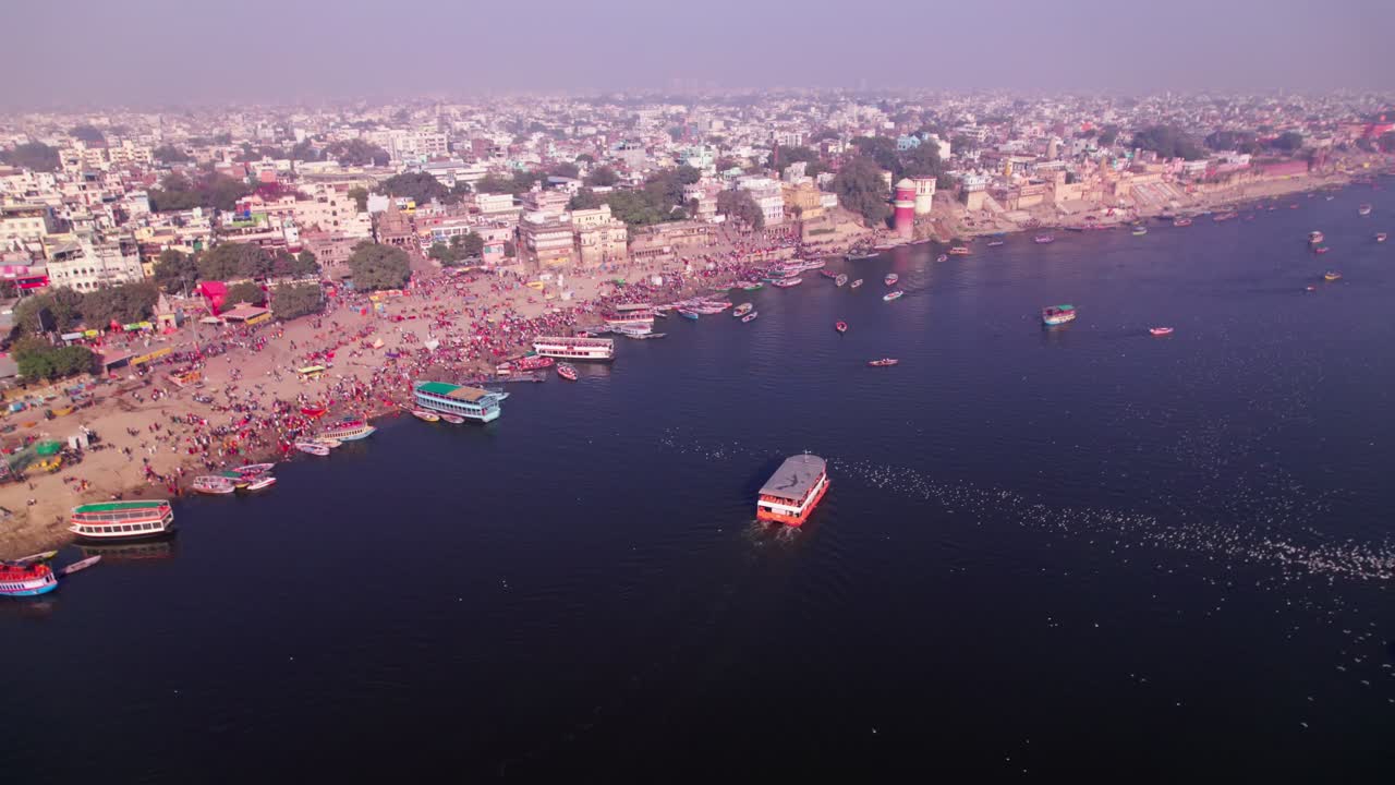 boats moving on ganga river with varanasi ghats and residential buildings at banaras, kashi, varanasi, uttar pradesh, india. day time, push in, tilt up, drone shot, 4k.
