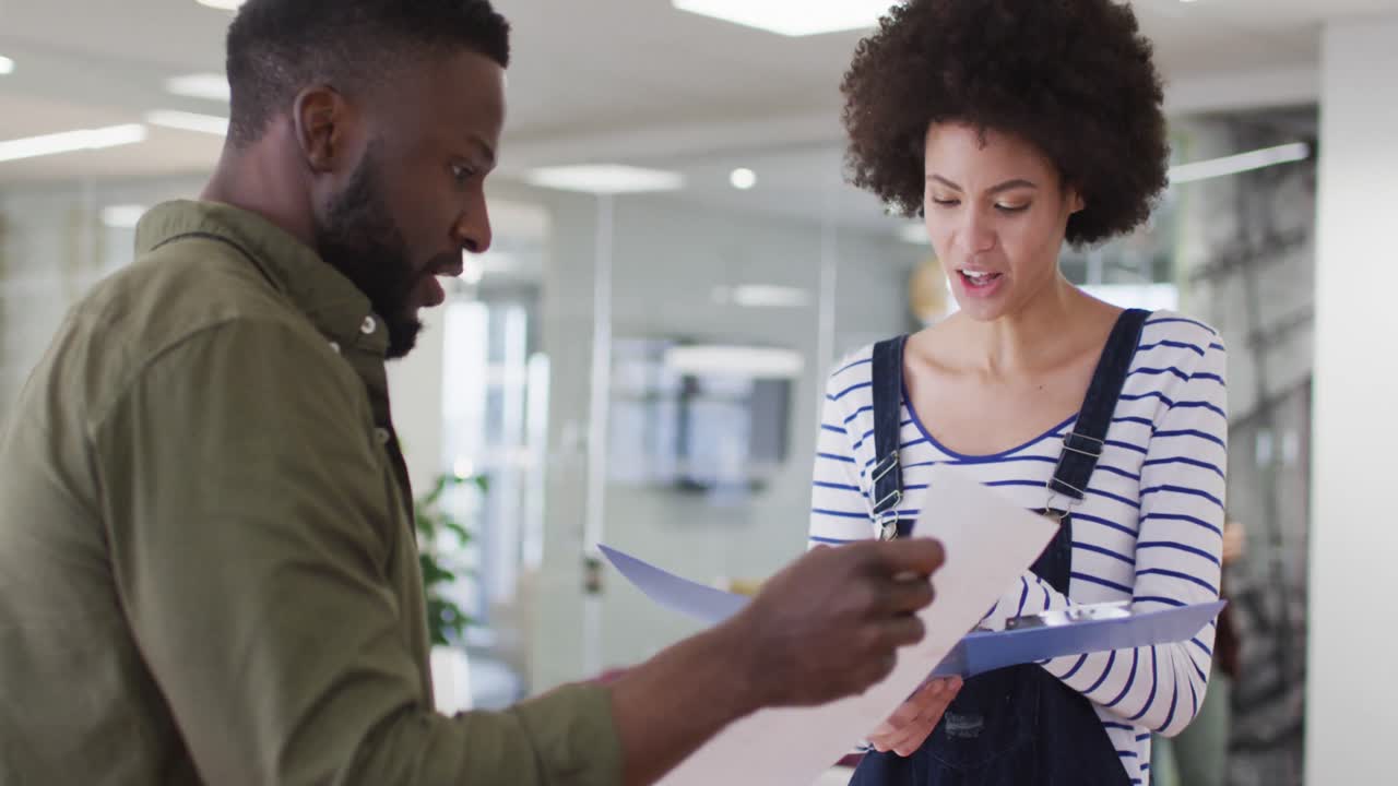 Two male and female african american colleagues having business talk in office