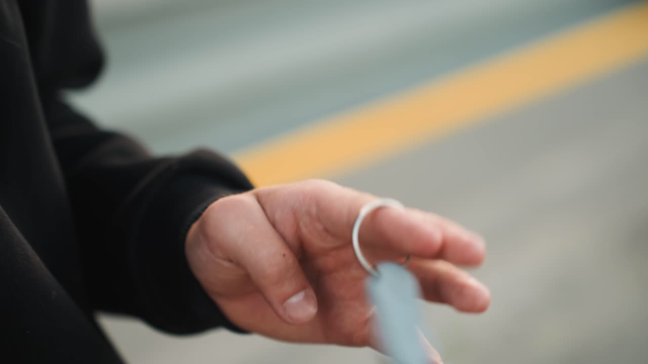 Adolescente che esegue illusioni con le dita all'aperto. Primo piano di mani giovanili con un anello che dimostrano giochi di destrezza con le dita. Inquadratura dettagliata di una persona giovane che mostra giochi di destrezza con le dita e un anello, con sfondo di una strada cittadina.