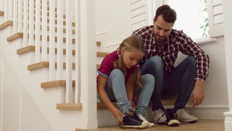 Father-helping-her-daughter-to-wear-shoes-on-stairs-in-a-comfortable-home-4k