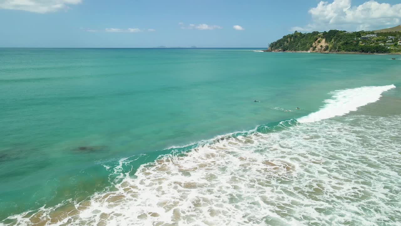 Ondas rolando suavemente na costa de uma praia de surf da Nova Zelândia.