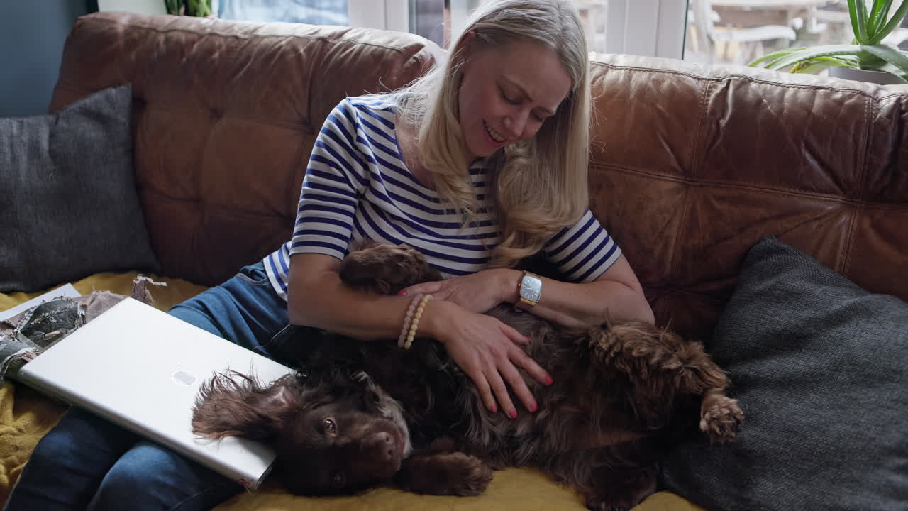 A woman petting her dog on the couch