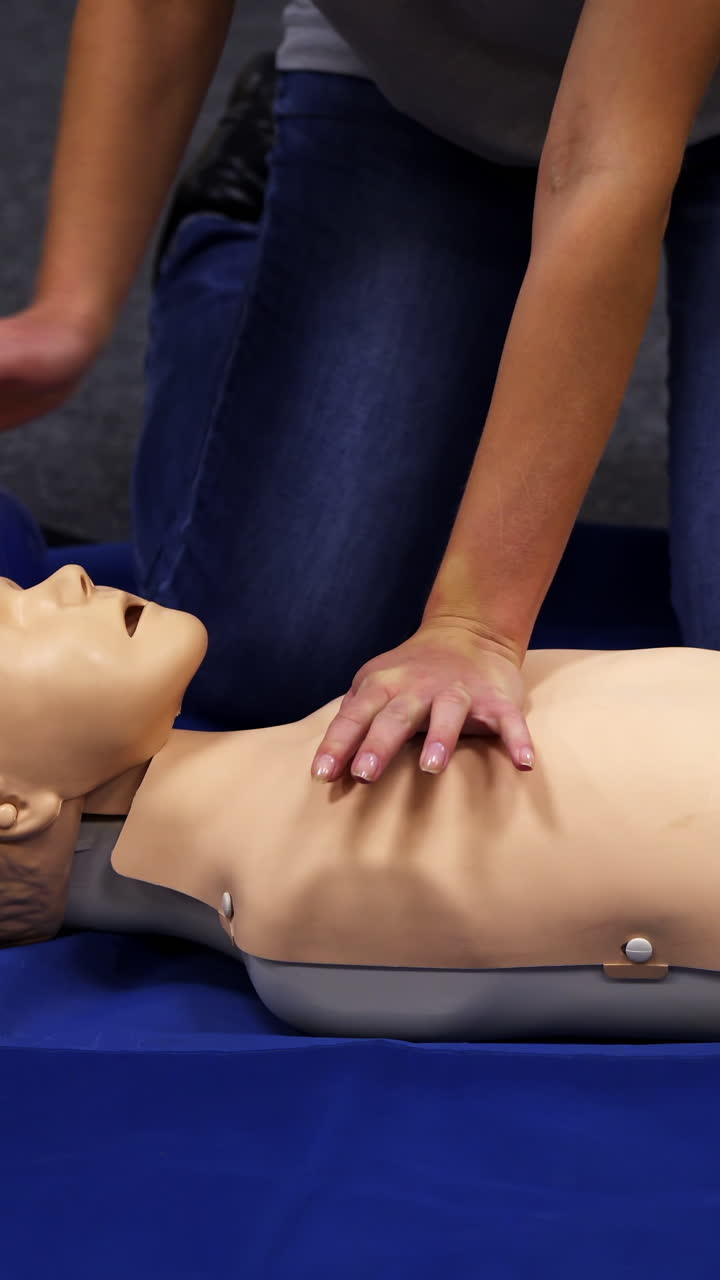 Baby CPR dummy first aid training. Paramedic performing cardiopulmonary resuscitation on baby dummy with chest compression. Vertical video