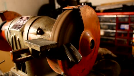 artesano utiliza una rueda eléctrica para moler una barra de metal en su taller de casa