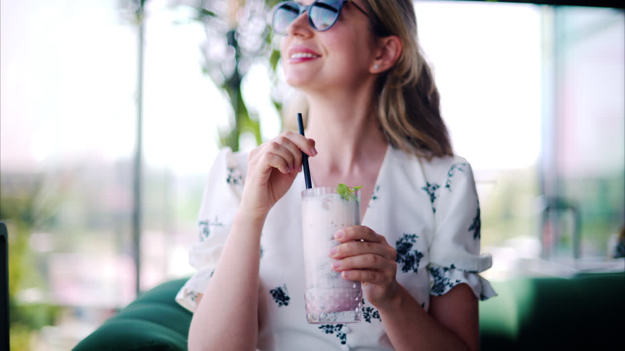 Woman drinking a strawberry drink with a black straw at a restaurant
