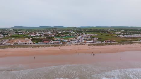 Playa-El-Palmar-En-Cádiz-España-Mientras-Los-Bañistas-Juegan-Bajo-El-Sol,-Pan-Aéreo