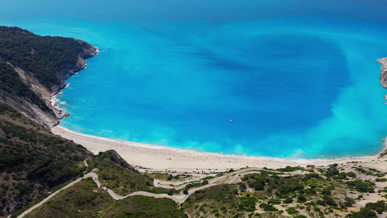 Veduta aerea panoramica delle acque blu turchese della spiaggia di Myrtos con scogliere calcaree, strade a tornanti, isola di Cefalonia, Mar Ionio.