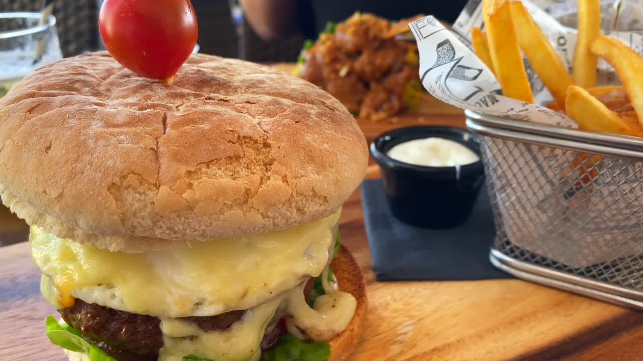 sabrosa hamburguesa con queso con patatas fritas y mayonesa, experiencia de comida en un restaurante, tiro de 4k