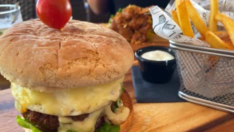 Sabrosa-Hamburguesa-Con-Queso-Con-Patatas-Fritas-Y-Mayonesa,-Experiencia-Gastronómica-En-Un-Restaurante,-Toma-De-4k