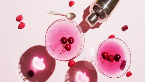 close up of drinks with cherries and shaker on white background