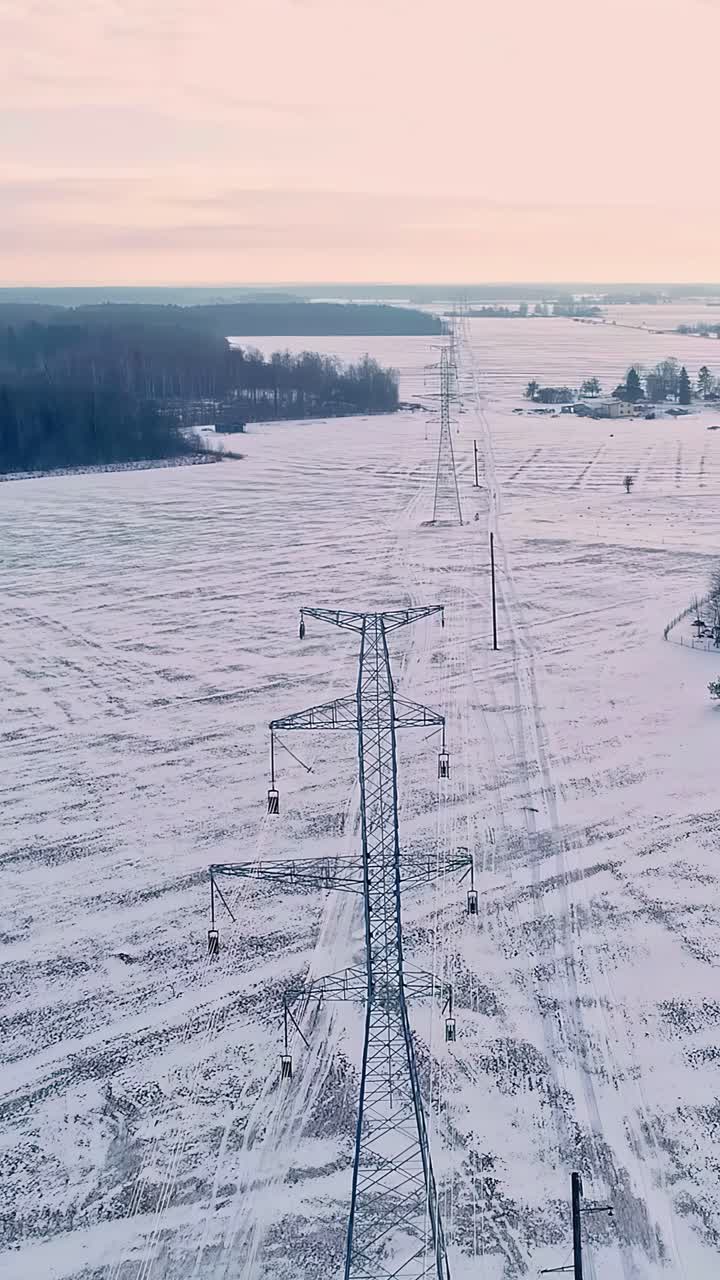Endless high voltage power lines in winter fields, aerial vertical view