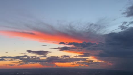 Aerial-view-of-a-huge-fading-cumulonimbus-in-the-sunset-with-a-colorful-sky-raken-from-a-jet-cockpit