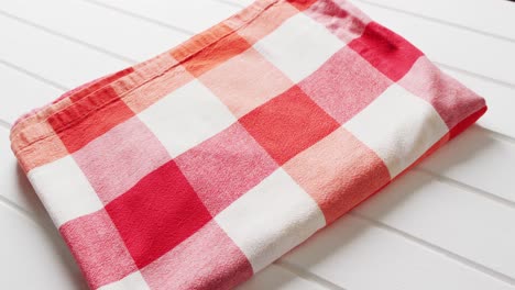 close up of folded red and white checkered blanket on white background with copy space