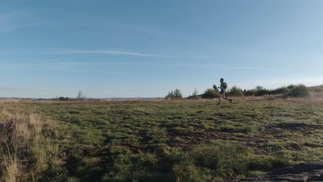 Weitwinkelaufnahme-Eines-Läufers,-Der-Bei-Sonnenaufgang-über-Das-Feld-Joggt---Zeitlupe