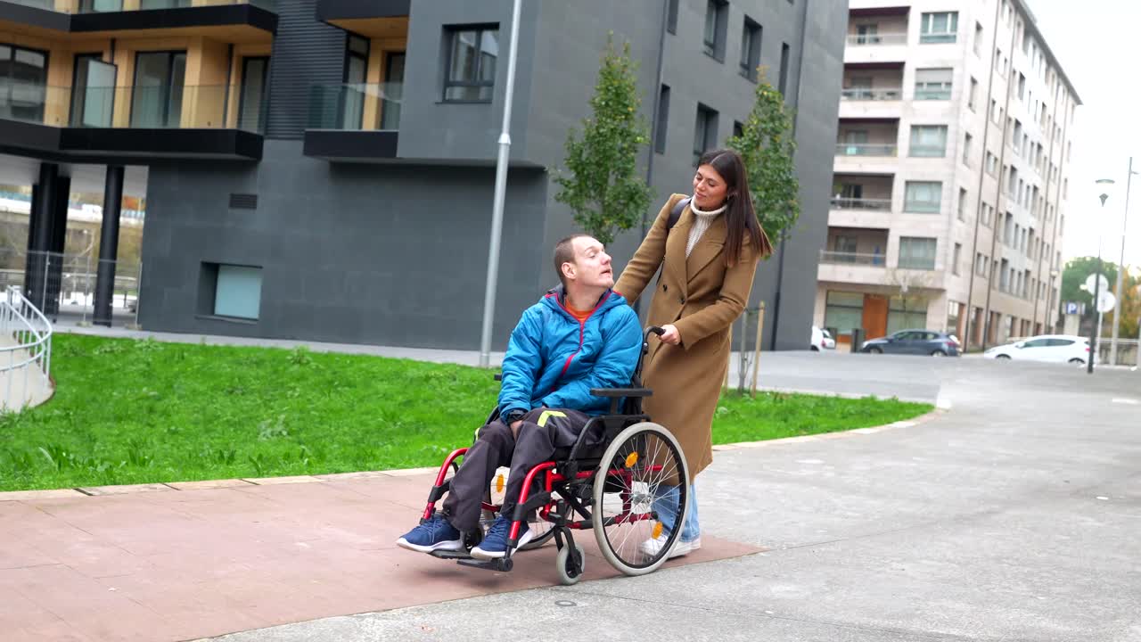 Caring Woman Assisting Man in Wheelchair Outdoors