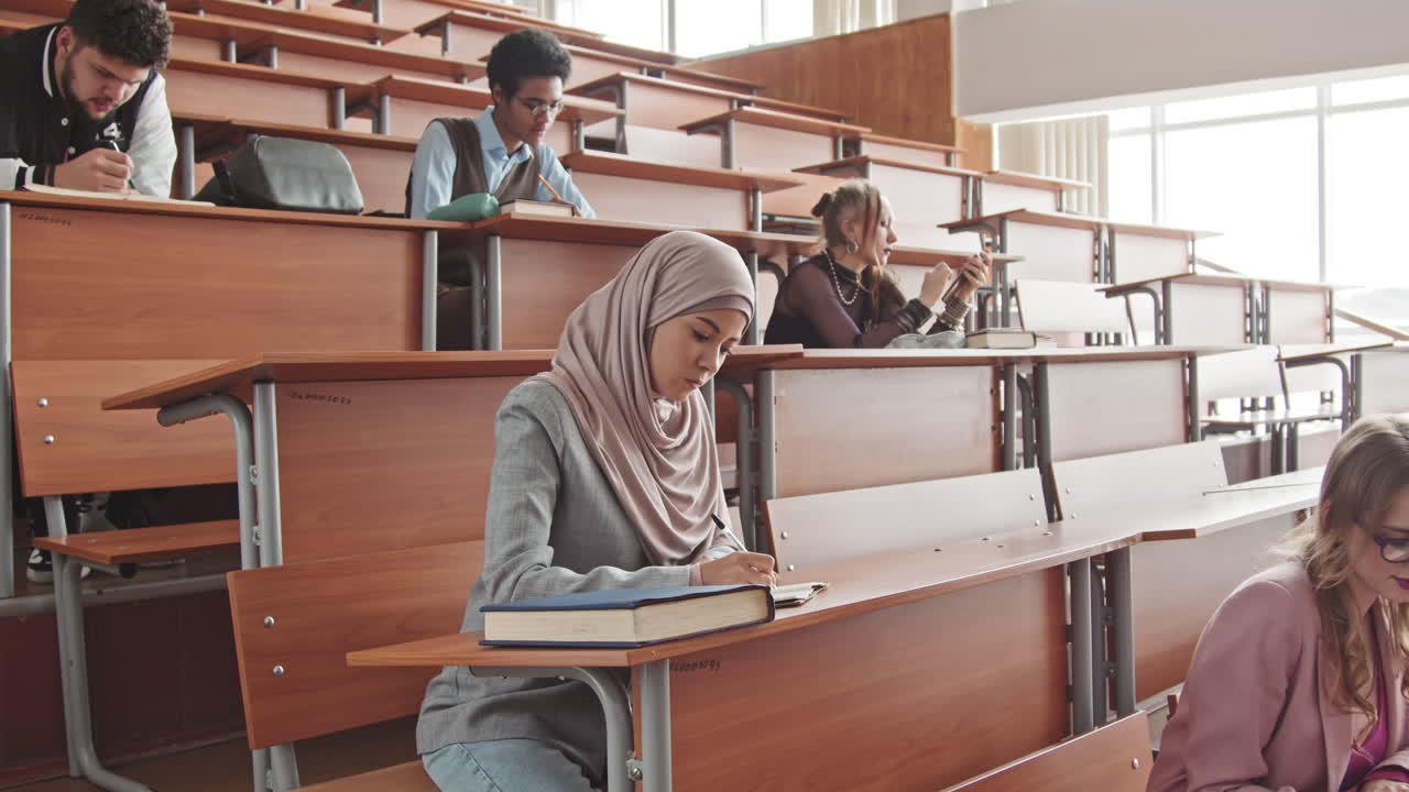 University Students Sitting in Rows at Desks in Lecture Hall