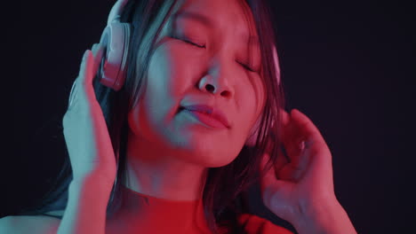 woman listening to music with headphones in neon light