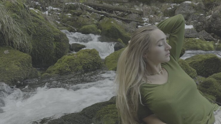 mujer relajándose junto a un arroyo de montaña