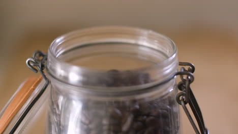 close up of pouring coffee beans into mason jar with lid