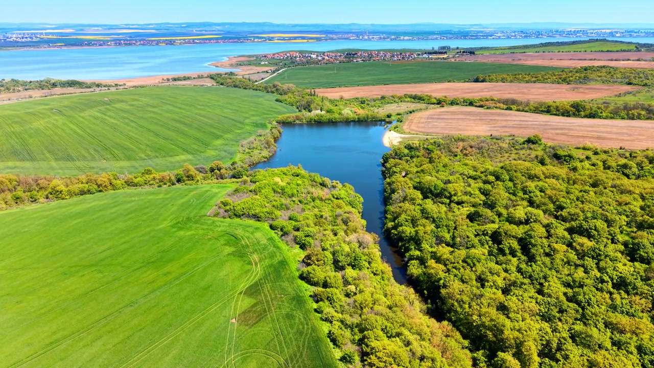 Panoramiczny widok z lotu ptaka na naturalne jezioro, las i zbiornik wodny. Szeroki krajobraz z wysokiej perspektywy, ukazujący zbiornik wodny, zielone lasy, pola uprawne i odległy horyzont.