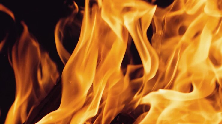 Falò che brucia di notte. Fiamme di fuoco su sfondo nero al rallentatore.