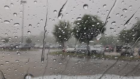 Dies-Ist-Ein-Kurzer-Videoclip-Von-Regen,-Der-Auf-Ein-Autofenster-Fällt-Und-Große-Tropfen-Und-Kleine-Wasserströme-Erzeugt,-Die-Am-Fenster-Herunterfließen