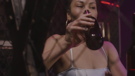 hermosa chica bebiendo cerveza y hablando con alguien en la discoteca