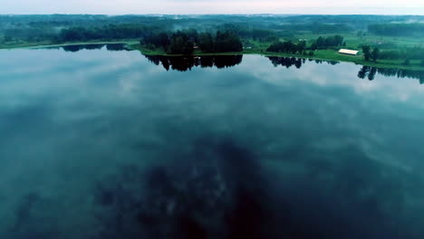 Una-Hermosa-Vista-Aérea-De-Un-Lago-Con-Agua-Azul-Y-Un-Gran-Bosque-Con-árboles-Verdes-En-El-Fondo