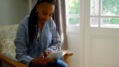 front view of young black woman using digital tablet in living room of comfortable home 4k